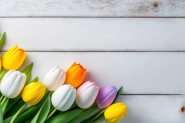 Multicolored tulips on a white wooden background top view. Mothers day, Valentines Day, Birthday. Generative AI.