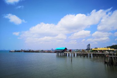 Okyanusun üzerindeki mavi gökyüzünde beyaz bulut kıyı şeridi ve dağları manzaralı.