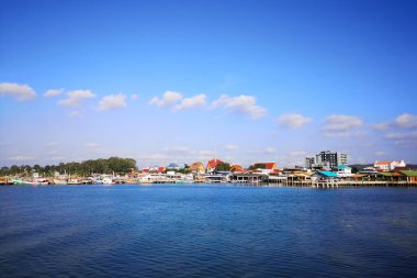 Okyanusun üzerindeki mavi gökyüzünde beyaz bulut kıyı şeridi ve dağları manzaralı.