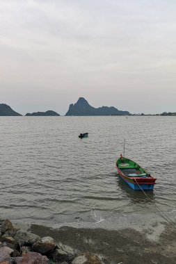Okyanusun üzerindeki mavi gökyüzünde beyaz bulut kıyı şeridi ve dağları manzaralı.