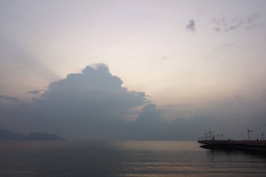 Okyanusun üzerindeki mavi gökyüzünde beyaz bulut kıyı şeridi ve dağları manzaralı.