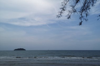 Okyanusun üzerindeki mavi gökyüzünde beyaz bulut kıyı şeridi ve dağları manzaralı.