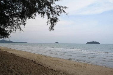 Okyanusun üzerindeki mavi gökyüzünde beyaz bulut kıyı şeridi ve dağları manzaralı.