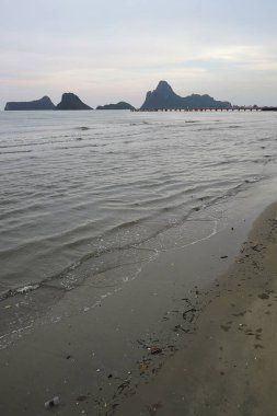 Okyanusun üzerindeki mavi gökyüzünde beyaz bulut kıyı şeridi ve dağları manzaralı.