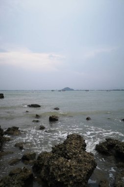 Okyanusun üzerindeki mavi gökyüzünde beyaz bulut kıyı şeridi ve dağları manzaralı.