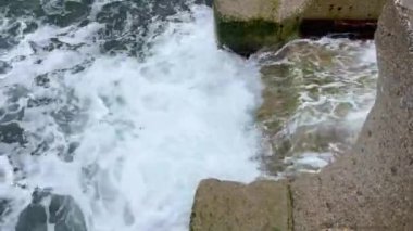 Güçlü fırtına dalgaları merdivenlere vuruyor dalgalı denize giriyor, yandan bakıyor. Çok güzel su sıçrattı. Yüksek kalite 4k görüntü