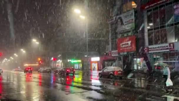 乌克兰基辅 2023年3月 雪灾期间城市街道上的交通 城市在暴风雪中 晚上有车和人 拿着雨伞穿过人行横道的女人 — 图库视频影像
