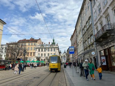 Lviv, Ukrayna - 18 Nisan 2023: Lviv sokaklarında insanlar. Vatandaşlar ve turistler Lviv 'deki Pazar Meydanı' nda yürüyüp dinleniyorlar. Şehir merkezinde eski bir tramvay. Yüksek kalite fotoğraf