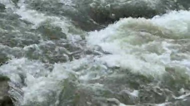 Soğuk ve hızlı dağ nehri kayaların etrafından geçiyor ve girdaplar yapıyor. Bir su akıntısında girdap. Hızlı akıntılı bir dağ nehri akıntısı. Yüksek kalite 4k görüntü