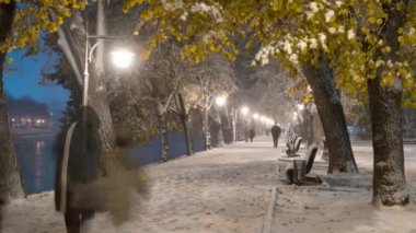 Yoğun kar yağışı sırasında aydınlanan Uzhgorod setinin resimli zaman dilimi, insanlar yürür, oynar ve ilk karın tadını çıkarırlar, kamera düzgün bir şekilde sağa doğru hareket eder. Yüksek kalite 4k görüntü