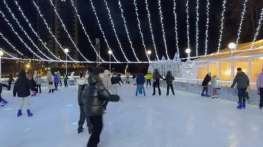 Kyiv, Ukrayna - 7 Ocak 2024: Mutlu ailelerin kış tatilinde buz pateni pistinde el ele tutuşarak eğlendikleri görüntüler. Yüksek kalite 4k görüntü