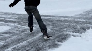 Erkek ve dişi bacaklar buz tutmuş gölde kayıyor. İnsanlar soğuk havalarda sporun tadını çıkarıyorlar. Kışın donmuş nehrin güzel yüzeyinde. Yüksek kalite 4k görüntü