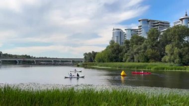 Ukrayna, Kiev - 16 Ağustos 2024: İnsanlar güneşli bir yaz gününde şehir nehri boyunca şişme kano ve kanoyla geziyorlar.. 