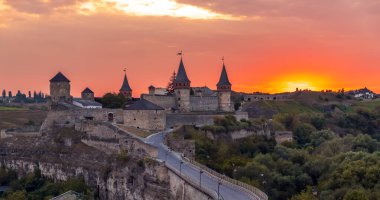 Kamianets Podilsky 'deki eski ortaçağ şatosunun görkemli günbatımı manzarası. Kamianets-Podilskyi kalesi alacakaranlıkta Smotrych Nehri kanyonundaki kayalık bir yarımadada duruyor.