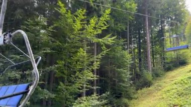 Boş bir kayak asansörü yazın güneşli bir kayak merkezine çam ormanının arka planına iniyor. Yüksek kalite 4k görüntü