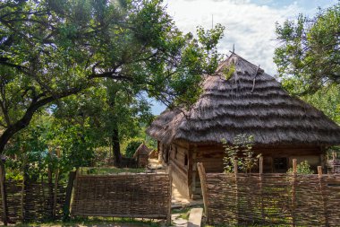 Kırsal kesimde sazdan çatılı eski bir geleneksel ev. Yazın antik Ukrayna köylü evi çitleri olan pitoresk bir bahçede. Yüksek kalite fotoğraf