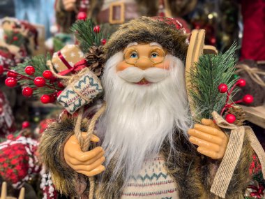 Dekoratif Noel Baba 'nın arka planda bulanık Noel süsleriyle beyaz bir yüzeyde durduğu şenlikli bir Noel gösterisi. Tatil evi dekorasyonu. Geleneksel Noel süsü. Yüksek kalite