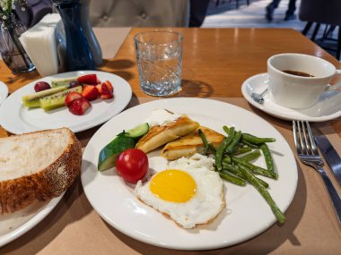Hotel Style Breakfast: Fried Egg, Blini with Sour Cream, Beans, and Fruit Salad.Dengeli Sabah Yemeği: Egg, Blini, Green Beans, Fresh Fruit, and Coffee. Yüksek kalite fotoğraf