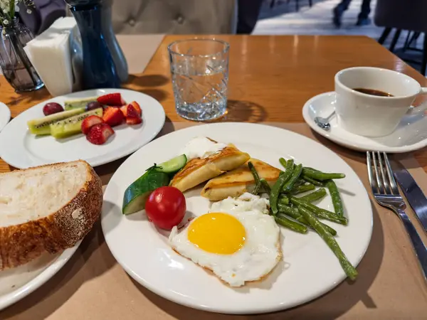 Hotel Style Breakfast: Fried Egg, Blini with Sour Cream, Beans, and Fruit Salad.Dengeli Sabah Yemeği: Egg, Blini, Green Beans, Fresh Fruit, and Coffee. Yüksek kalite fotoğraf