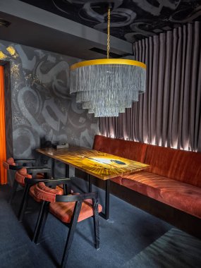 Modern Restoran İçi Kadife Koltuklar, Epoksi Reçine Masası ve Sınır Bilim Avizesi. Lüks Karanlık İç Tasarım. Eşsiz Ahşap Masa, Kadife Sandalyeler, Glam Lighting. Yüksek kalite fotoğraf