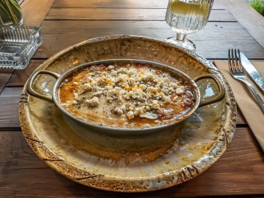 Feta Peynirli Lezzetli Sıcak Güveç bir açık hava restoranında Rustik Pan 'da servis ediliyor. Al Fresco Yemeği: Yaz Kafe Terasında Tahta Masada Pişmiş Bir Tabak. Yüksek kalite fotoğraf