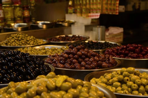 Appetizing marinated olives in assortment. Green and black olives at a market in Tel Aviv. Large beautiful pickled olives.