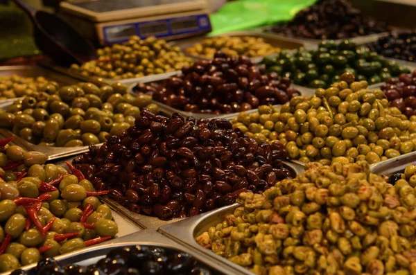 Appetizing marinated olives in assortment. Green and black olives at a market in Tel Aviv. Large beautiful pickled olives.