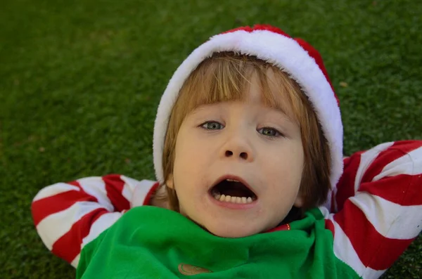 Słodki Pozytywny Chłopiec Kapeluszu Santa Claus Kostium Elfa Leży Zielonym — Zdjęcie stockowe