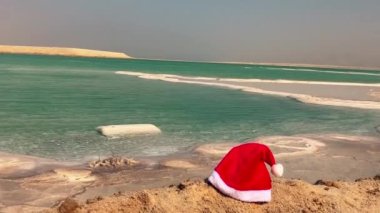 İsrail 'de Ölü Deniz kıyısında Noel Baba' nın şapkası. Kar yerine beyaz tuz. Kışın yaz. Noel tatili konsepti, yaza kış seyahati, tropikal yerler, çölde yeni yıl..