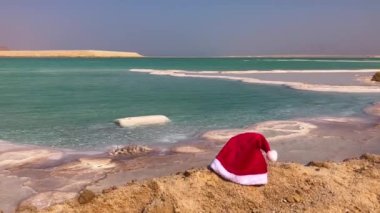 İsrail 'de Ölü Deniz kıyısında Noel Baba' nın şapkası. Kar yerine beyaz tuz. Kışın yaz. Noel tatili konsepti, yaza kış seyahati, tropikal yerler, çölde yeni yıl..