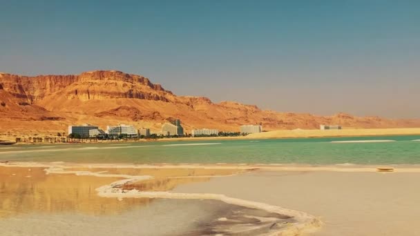 イスラエルの死海にあるEin Bokekリゾート パノラマユダヤ砂漠の雄大な山々 豪華なホテルの雪の白い建物 ターコイズブルーの海と塩キノコ — ストック動画