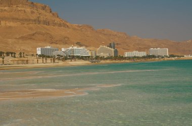 İsrail 'deki Ölü Deniz kıyısındaki Ein Bokek tatil köyü. Musevi Çölü 'nün görkemli dağları, lüks otellerin kar beyazı binaları, turkuaz deniz ve tuz mantarları..
