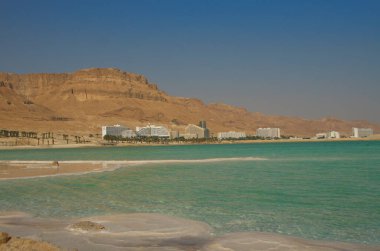 İsrail 'deki Ölü Deniz kıyısındaki Ein Bokek tatil köyü. Musevi Çölü 'nün görkemli dağları, lüks otellerin kar beyazı binaları, turkuaz deniz ve tuz mantarları..
