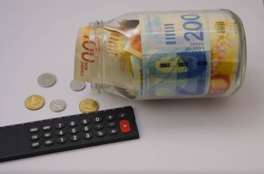 Cam kavanozda yeni İsrail şekelleri. Hesap makinesi, büyüteç. Bozuk paralar 
