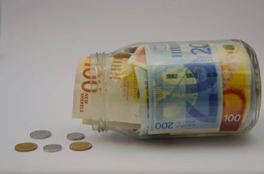 Cam kavanozda yeni İsrail şekelleri. Hesap makinesi, büyüteç. Bozuk paralar 