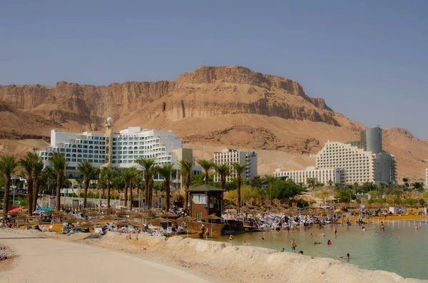 stock image ISRAEL. DEAD SEA Ein Bobek. november 2022. Resort public beach and people swimming. Israeli health resort. Therapeutic mud and salt water Mountains and luxury hotels in the background