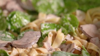 İtalyan makarnası pişirmek. Şampiyonlarla karıştırılmış Fettuccine ve fesleğenli krema. Şef makarna maşasıyla makarnayı karıştırır. Yakın çekim, iştah açıcı ağır çekim.
