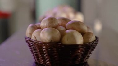 Hasır sepette şampiyon mantarları. Beyaz arka planda yakın çekim, yavaş çekim. Arka arkaya üç sepet mantar. Yemek yapmak için gerekli malzemeler. Kaydırıcıdan ateş etmek