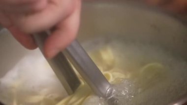 Makarna yapma süreci. Aşçı makarnayı maşayla kaynar sudan çıkarır. Fetuçin suda kaynatılır, al dente. Suyun kaynama noktası - makarna pişirme