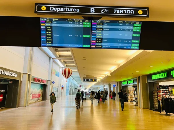 Tel Aviv 'de. İsrail. Ben Gurion Havaalanı. Aralık 2022. Terminaldeki insanlar, uçuş çizelgesi olan kurul. İsrail seyahati kavramı