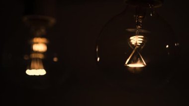 Karanlıkta iki ampul yanıyor ve sönüyor. Tesla ampulü. Elektriksel yakın çekim. Enerji sistemi, ışık, elektrik kesintisi.