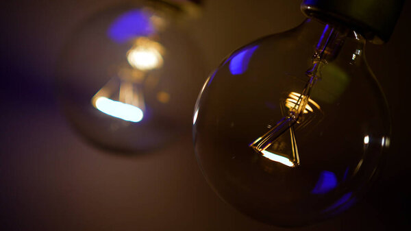 Tesla glass light bulb in the dark. Incandescent thread. Concept: energy saving, blackout, lack of electricity, new idea, light in the dark