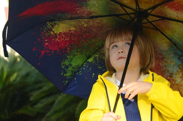 Boy preschooler with a bright umbrella in a yellow raincoat. The child is going for a walk in the rain. Puddle walks.