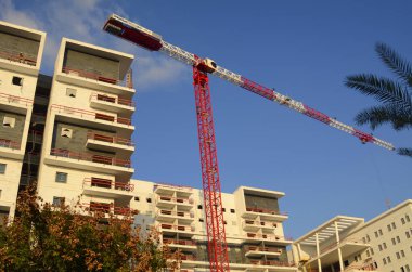 Güzel bir manzara. İnşaat alanı. Beyaz bina ve kırmızı inşaat vinci. Mesaj için yer var. İsrail 'de gayrimenkul. Ev almak, ipotekli bir daire, krediyle.