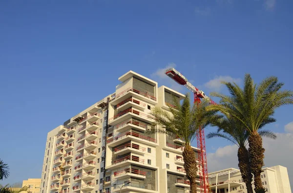 Beautiful landscape - construction site. White building and red construction crane. Space for text. Real estate in Israel. Buying a home, an apartment in a mortgage, on credit