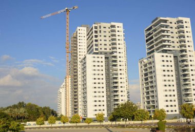 Konforlu bir yerleşim yeri. Yüksek katlı, modern apartmanlar. İnşaat vinci. Evin yanındaki turuncu bahçe. Konsept: emlak yatırımı, ev satın alma, kredi, ipotek.