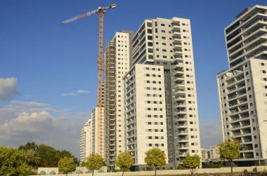 Konforlu bir yerleşim yeri. Yüksek katlı, modern apartmanlar. İnşaat vinci. Evin yanındaki turuncu bahçe. Konsept: emlak yatırımı, ev satın alma, kredi, ipotek.