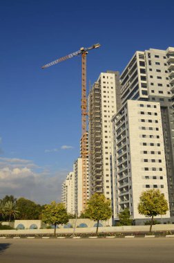 Konforlu bir yerleşim yeri. Yüksek katlı, modern apartmanlar. İnşaat vinci. Evin yanındaki turuncu bahçe. Konsept: emlak yatırımı, ev satın alma, kredi, ipotek.