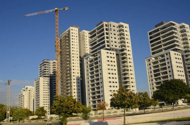 Konforlu bir yerleşim yeri. Yüksek katlı, modern apartmanlar. İnşaat vinci. Evin yanındaki turuncu bahçe. Konsept: emlak yatırımı, ev satın alma, kredi, ipotek.