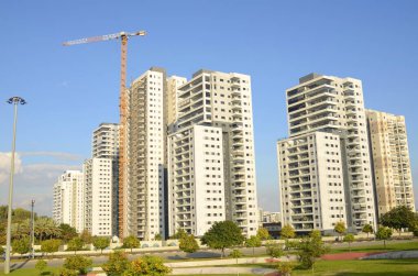 Konforlu bir yerleşim yeri. Yüksek katlı, modern apartmanlar. İnşaat vinci. Evin yanındaki turuncu bahçe. Konsept: emlak yatırımı, ev satın alma, kredi, ipotek.